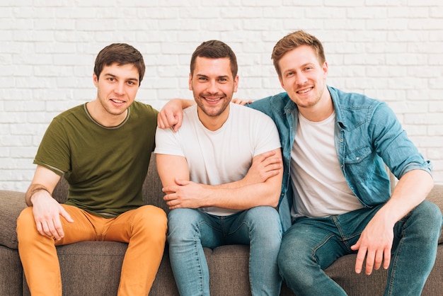 Portrait de sourire des amis hommes assis sur le canapé