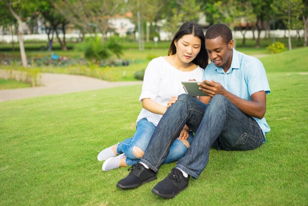 Portrait de sourire couple multiethnique en réseau sur le touchpad.