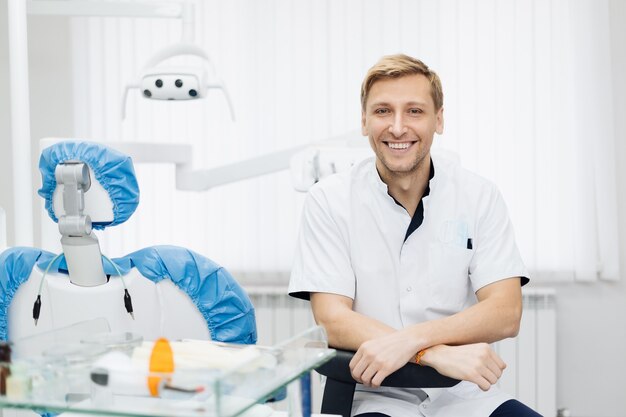 Portrait de sourire dentiste homme caucasien posant au cabinet dentaire moderne.