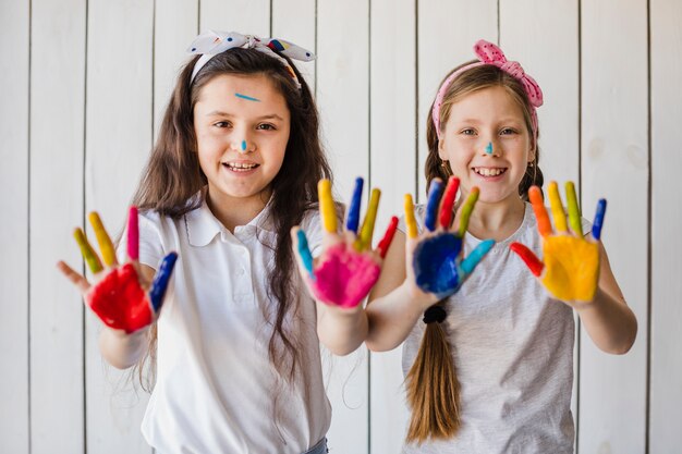 Portrait de sourire deux filles montrant des mains peintes colorées à la recherche d&#39;appareil photo