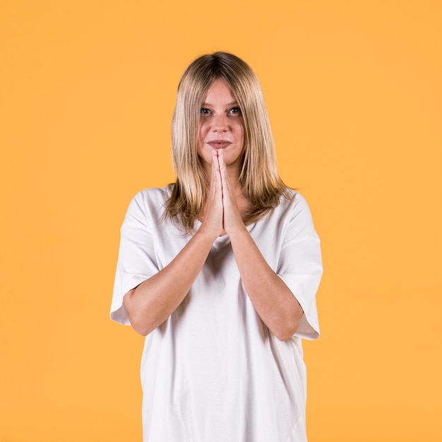 Portrait, de, sourire, jeune femme, à, prier, geste, debout, contre, mur jaune