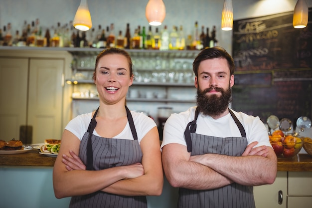 Portrait de sourire serveur et serveuse debout au comptoir