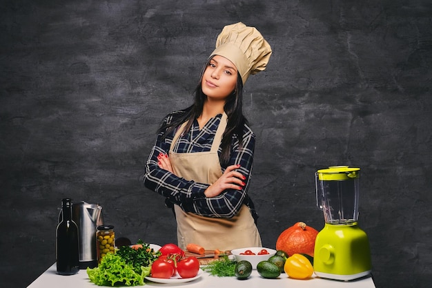 Photo gratuite portrait en studio du chef cuisinier féminin à la table avec beaucoup de légumes.