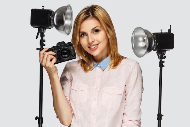 Photo gratuite portrait en studio d'une femme blonde positive avec appareil photo avec équipement photo sur fond.