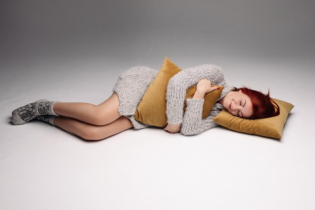 Portrait en studio d'une femme dans un chandail serrant un oreiller