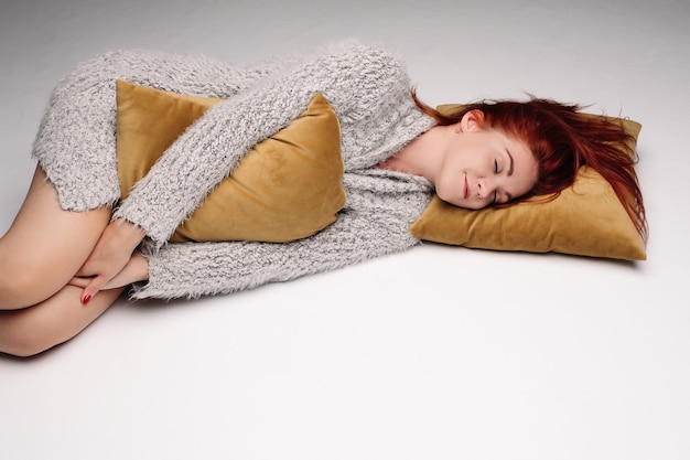 Portrait en studio d'une femme dans un chandail serrant un oreiller