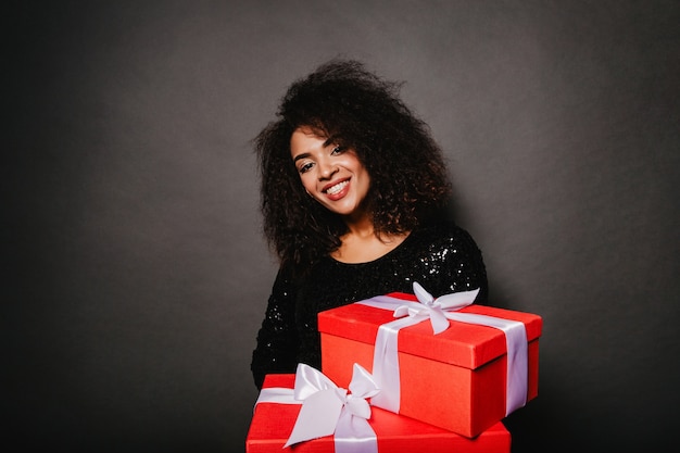 Photo gratuite portrait en studio de femme frisée heureuse tenant des cadeaux