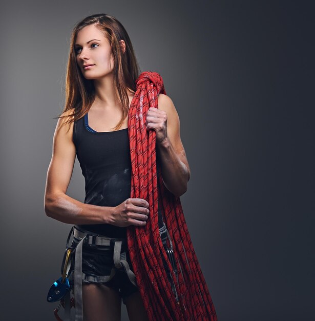 Portrait en studio d'une femme grimpante libre tient, corde d'escalade sur fond gris.