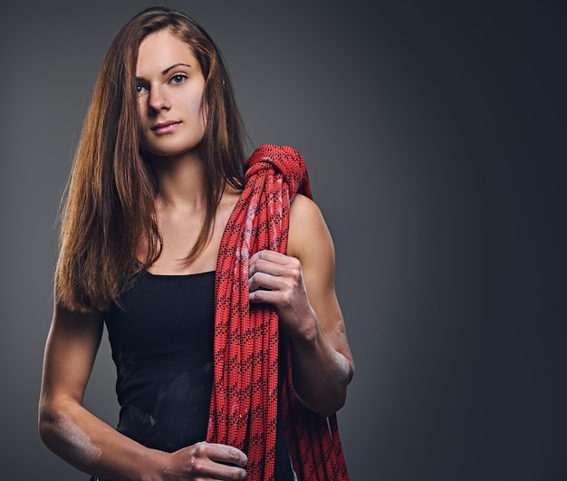 Portrait en studio d'une femme grimpante libre tient, corde d'escalade sur fond gris.