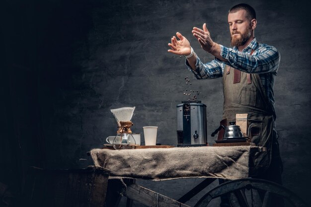 Portrait en studio d'un homme barbu rousse préparant un cappuccino dans une machine à café.