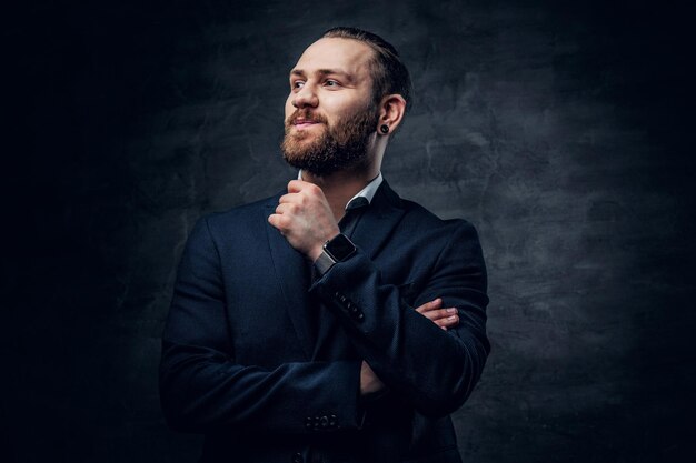 Portrait en studio d'un homme barbu vêtu d'une veste bleue sur fond de vignette grise.