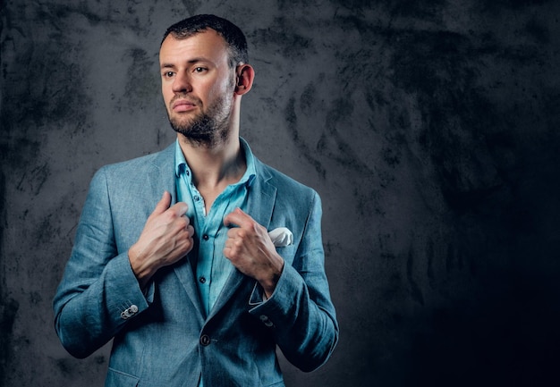 Portrait en studio d'un homme en costume gris clair sur fond gris.