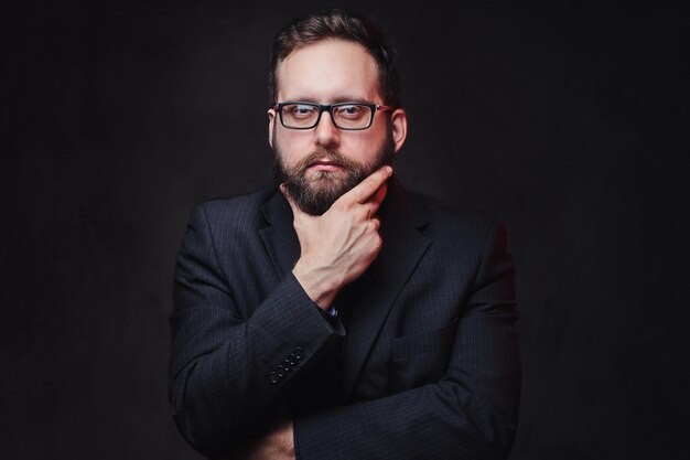 Portrait en studio d'un homme dodu sérieux dans des lunettes sur fond gris.