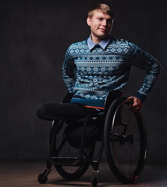Photo gratuite portrait en studio d'un homme en fauteuil roulant sur fond gris.
