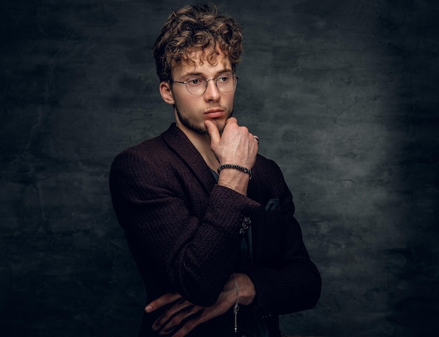 Portrait en studio d'un homme intelligent à lunettes vêtu d'une veste marron.