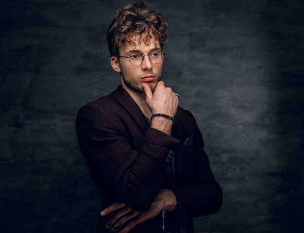 Portrait en studio d'un homme intelligent à lunettes vêtu d'une veste marron.