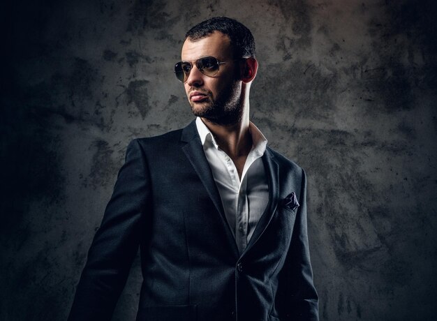 Portrait en studio d'un homme moderne sérieux en chemise blanche et veste d'affaires sur fond gris.