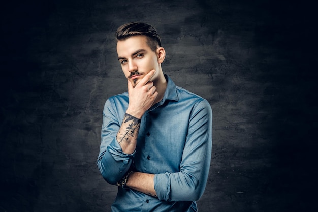 Portrait en studio d'un homme réfléchi et décontracté avec un tatouage sur son bras.