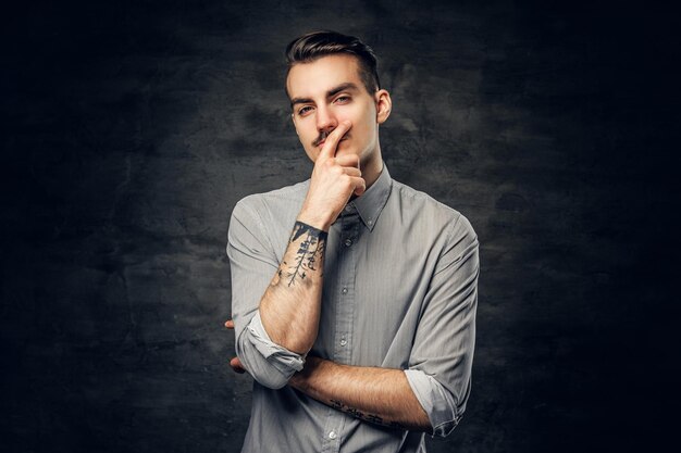 Portrait en studio d'un homme réfléchi et décontracté avec un tatouage sur son bras.