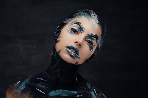 Portrait en studio de jeune femme avec maquillage coloré et art peint sur un cou.