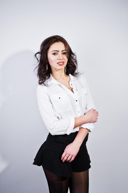 Portrait en studio de jeune fille brune en blouse blanche sur fond blanc