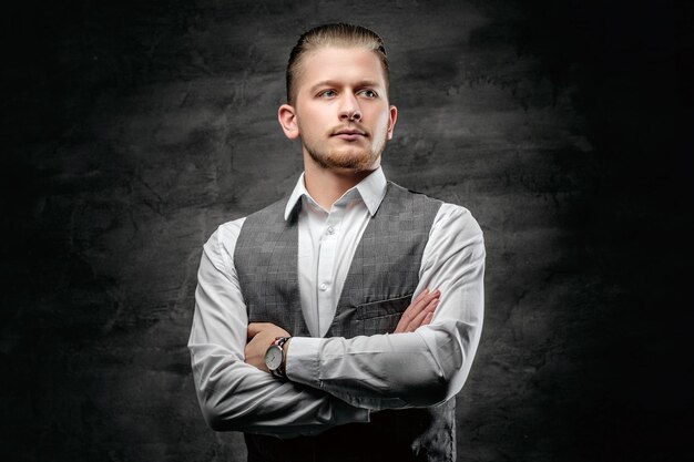 Portrait en studio de jeune homme d'affaires en chemise sans manches blanche sur fond gris foncé.