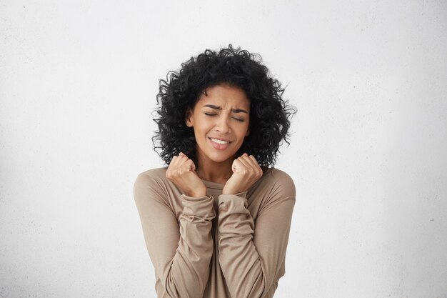 Portrait à la taille d'une jeune femme à la peau foncée jubilatoire et vivace, acclamant d'excitation