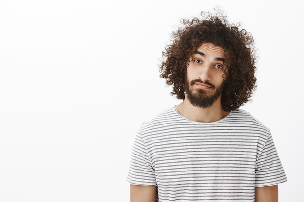 Portrait de taille de sympathique petit ami hispanique mignon avec barbe et coiffure afro, portant un t-shirt rayé décontracté