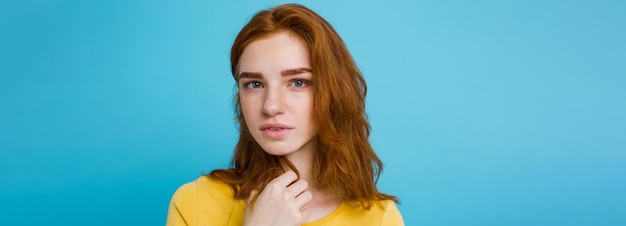 Portrait de tête de fille heureuse aux cheveux roux gingembre avec des taches de rousseur souriant regardant la caméra bleu pastel