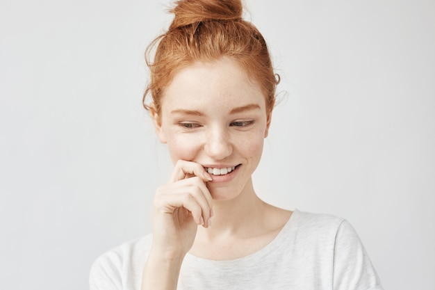 Portrait de timide belle femme aux cheveux foxy et taches de rousseur souriant.