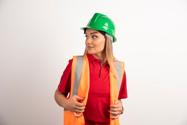 Portrait d'une travailleuse posant avec casque sur fond blanc.