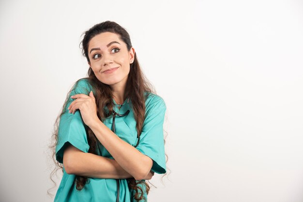 Portrait d'une travailleuse de la santé posant sur un mur blanc.