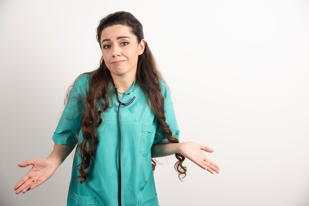 Portrait d'une travailleuse de la santé posant sur un mur blanc.