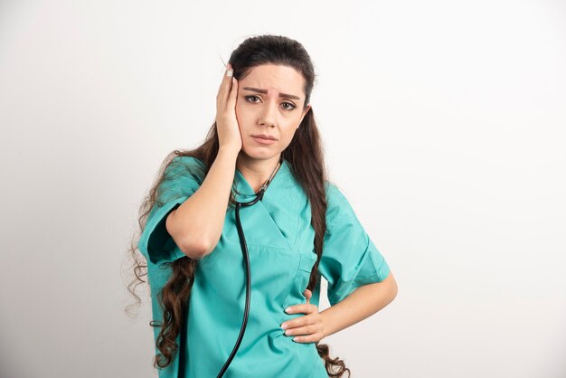 Portrait d'une travailleuse de la santé touchant sa tête.