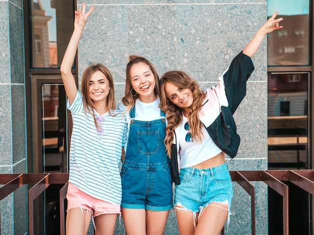 Portrait de trois jeunes belles filles hipster souriantes dans des vêtements d'été à la mode. Sexy, insouciant, femmes, poser, rue, positif, modèles, amusant, étreindre