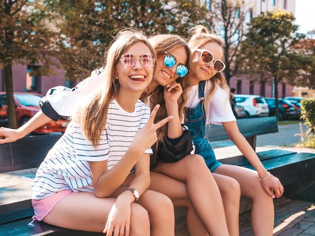 Portrait de trois jeunes belles filles hipster souriantes dans des vêtements d'été à la mode. Sexy, insouciant, femmes, poser, rue, positif, modèles, amusant, lunettes soleil, étreindre