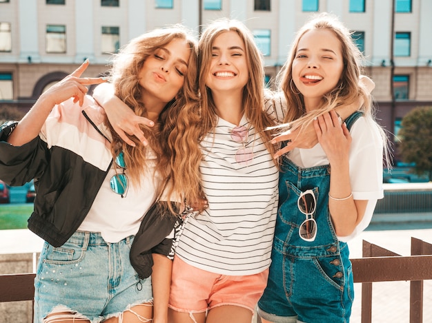 Portrait de trois jeunes belles filles hipster souriantes dans des vêtements d'été à la mode. Sexy, insouciant, femmes, poser, rue, positif, modèles, amusant