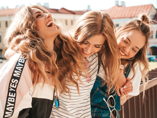 Portrait de trois jeunes belles filles hipster souriantes dans des vêtements d'été à la mode. Sexy, insouciant, femmes, poser, rue, positif, modèles, amusant