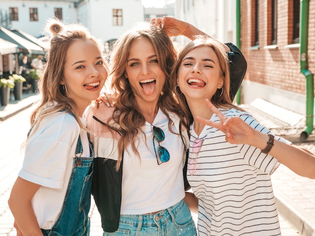 Portrait de trois jeunes belles filles hipster souriantes dans des vêtements d'été à la mode. Sexy, insouciant, femmes, poser, rue, positif, modèles, amusant