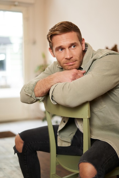 Photo gratuite portrait vertical d'un bel homme masculin assis sur une chaise regardant de côté en attendant une commande dans