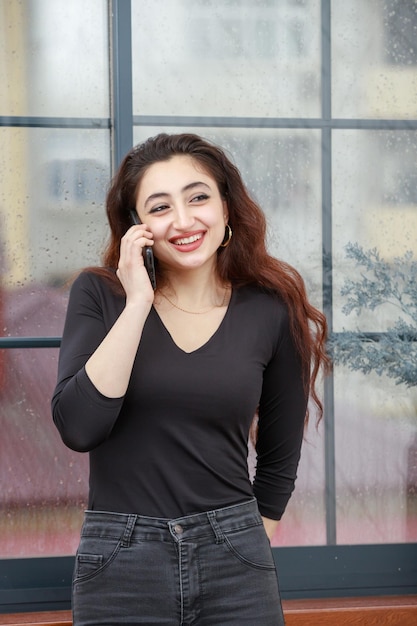 Portrait vertical d'une jeune femme parlant au téléphone et souriant