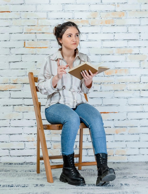Portrait vertical de jeune fille tenant un livre et pensant Photo de haute qualité
