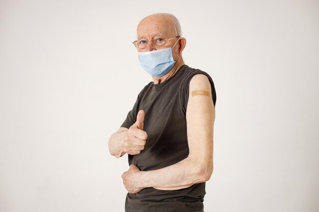 Portrait d'un vieil homme avec un pansement sur une épaule isolé sur fond blanc