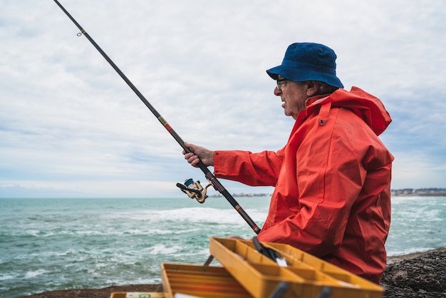 Portrait d'un vieil homme pêchant dans la mer. Concept de pêche.
