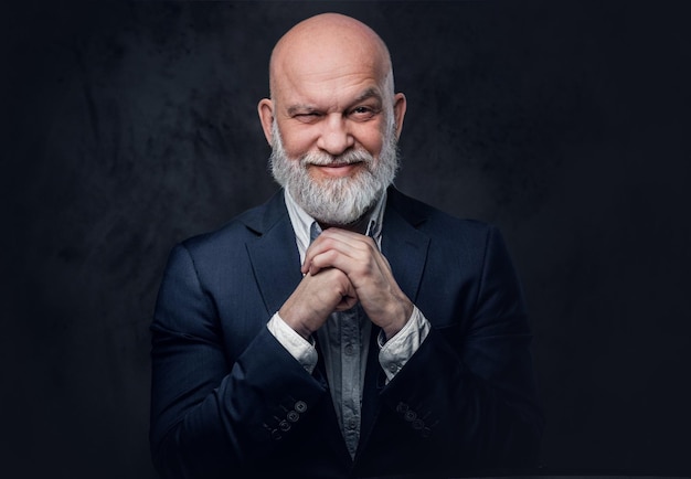 Portrait d'un vieil homme sans poils regardant la caméra sur fond de studio sombre.