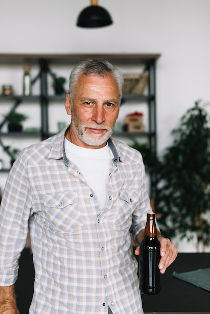 Photo gratuite portrait d'un vieil homme tenant une bouteille de bière à la main