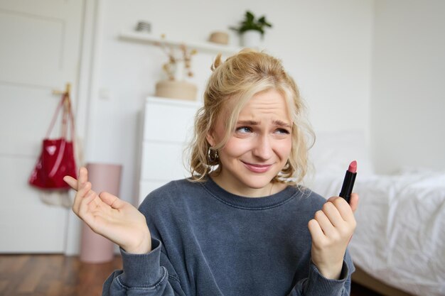 Portrait d'une vloggeuse déçue montrant du rouge à lèvres et haussant les épaules en enregistrant