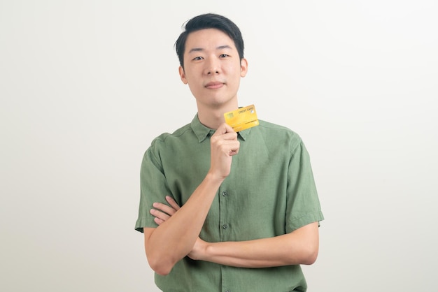 Portrait young asian man holding credit card sur fond blanc