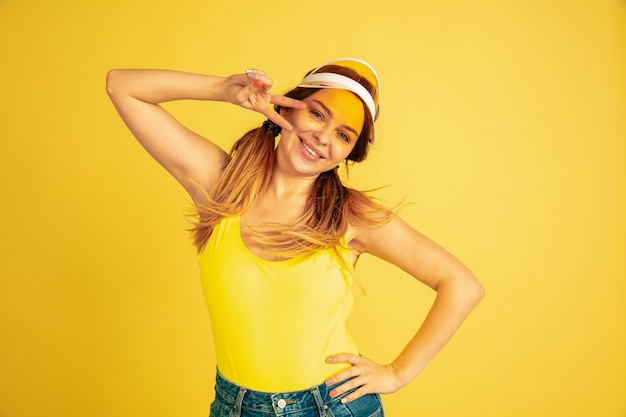 Posant mignon, souriant. Portrait de femme caucasienne sur fond de studio jaune.