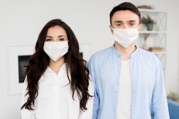 Photo gratuite pose de couple à la maison avec des masques